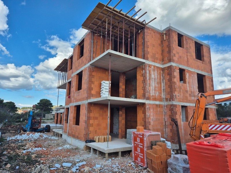 Vonkajší pohľad na rozostavaný bytový dom s červenými tehlami