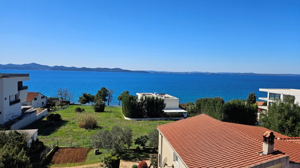 Strešná terasa s výhľadom na bazén a more pri západe slnka