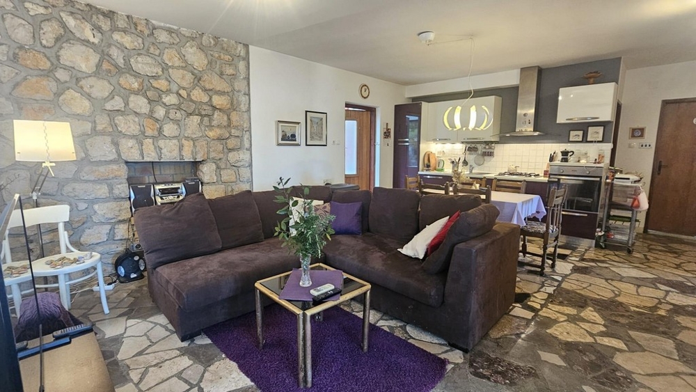 Obývacia izba so stenou z prírodného kameňa a kuchyňou