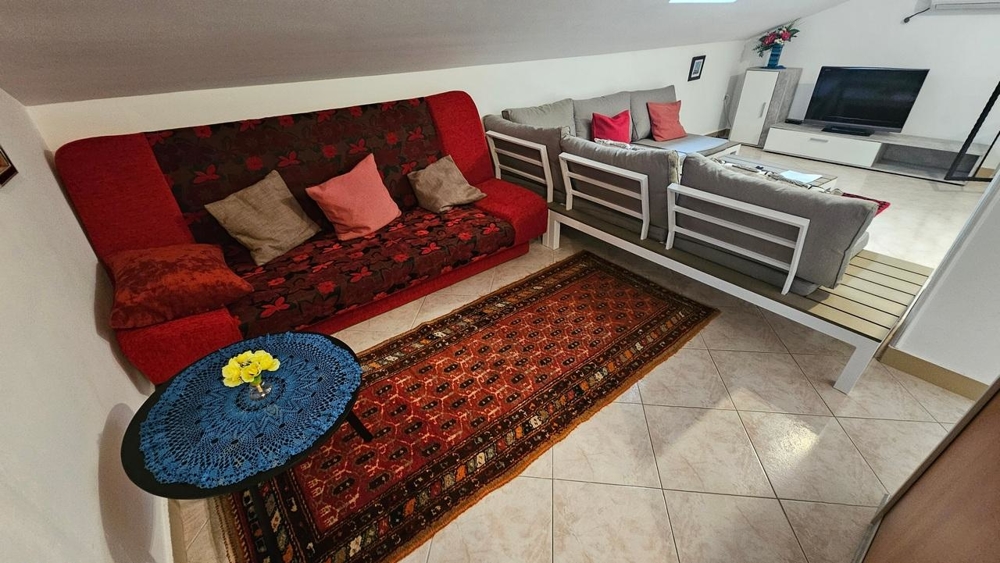 Obývacia izba v podkroví so sedačkou a televízorom