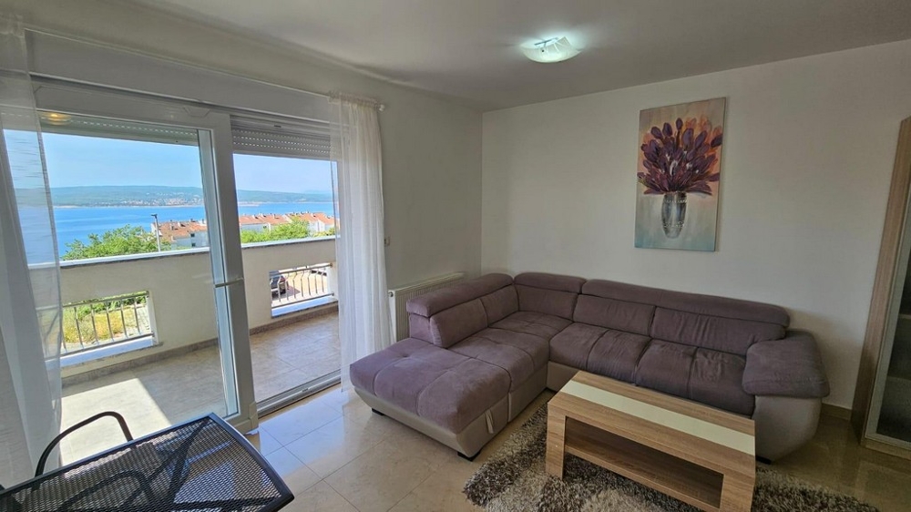 Zariadená obývacia izba s výhľadom na more.