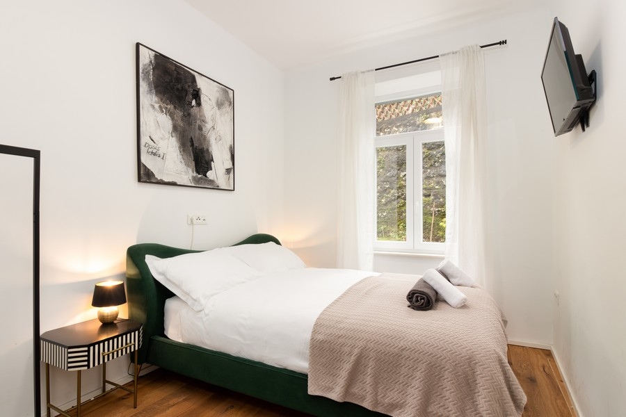 Spálňa so zelenou posteľou a nočným stolíkom