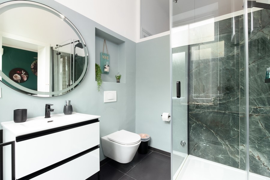 Kúpeľňa s okrúhlym zrkadlom a skleneným sprchovacím kútom