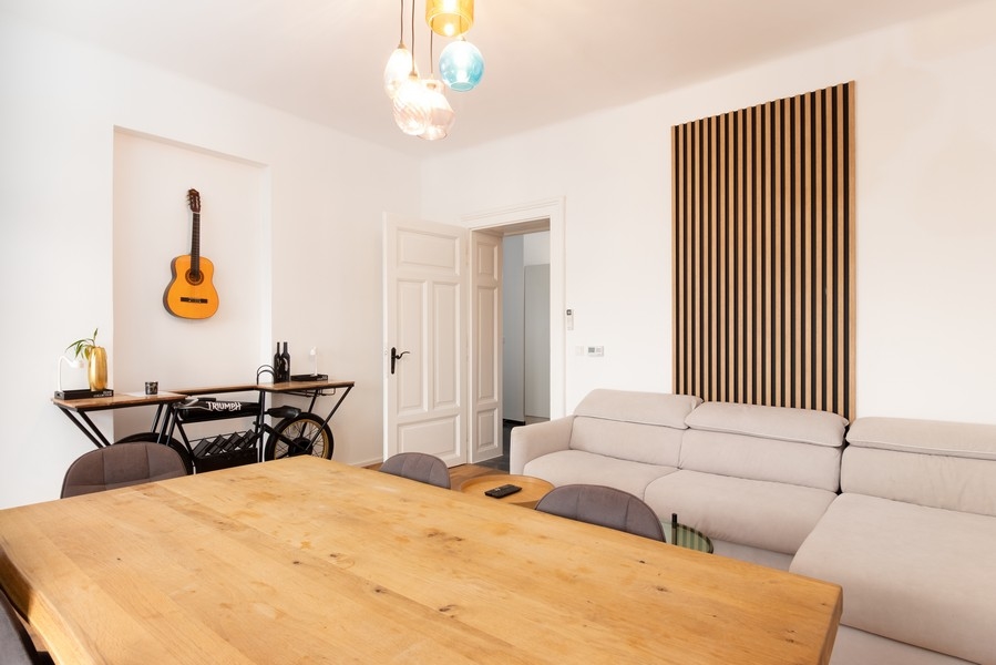 Obývacia časť so sedačkou, dreveným stolom a obkladom stien