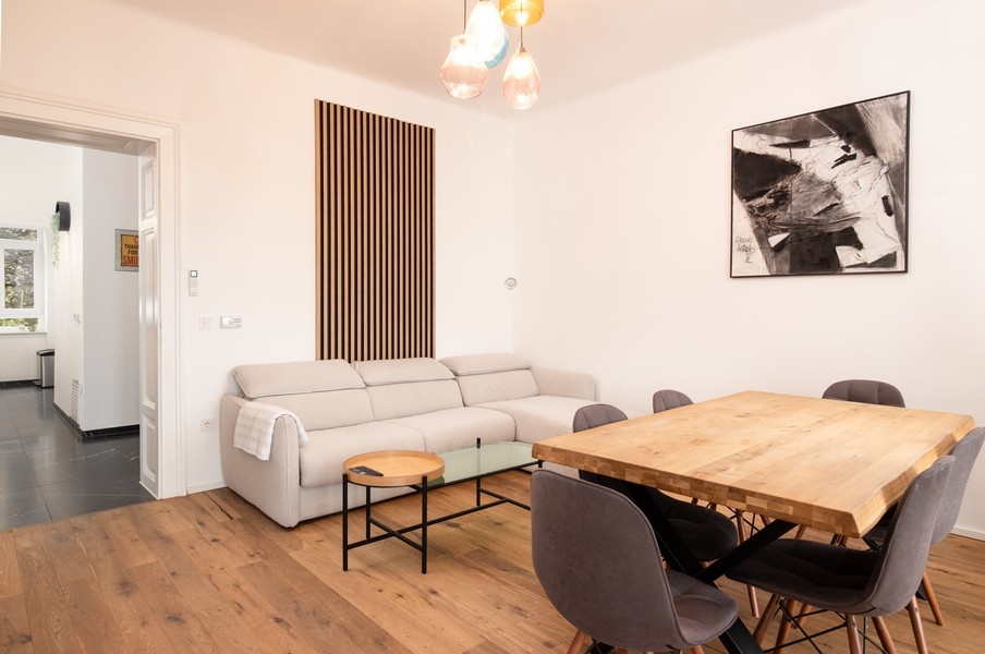 Obývacia izba s pohovkou, umením na stene a drevenou podlahou