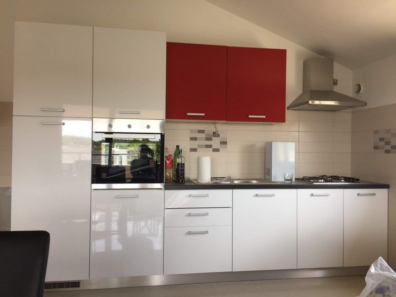 Vybavená kuchyňa s červenými hornými skrinkami