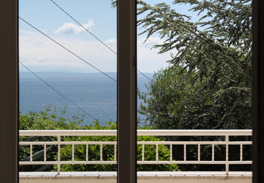 Výhľad na more z balkóna cez veľké presklené dvere
