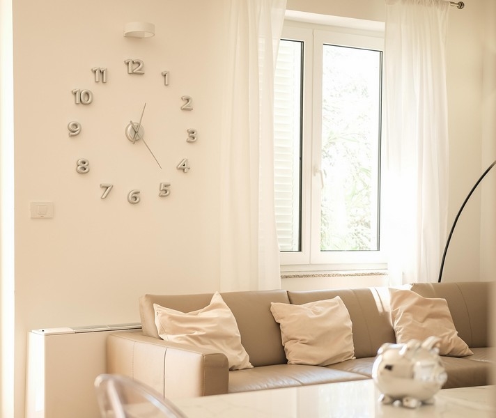 Obývacia izba s nástennými hodinami a výhľadom do zelene