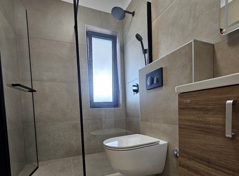 Moderná kúpeľňa so sprchovacím kútom a oknom