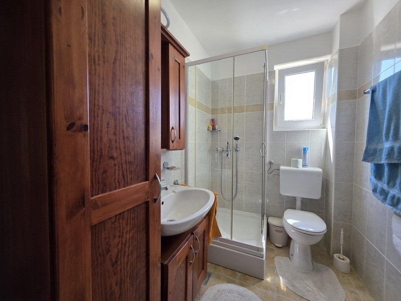 Kúpeľňa so sprchovacím kútom a drevenou skriňou