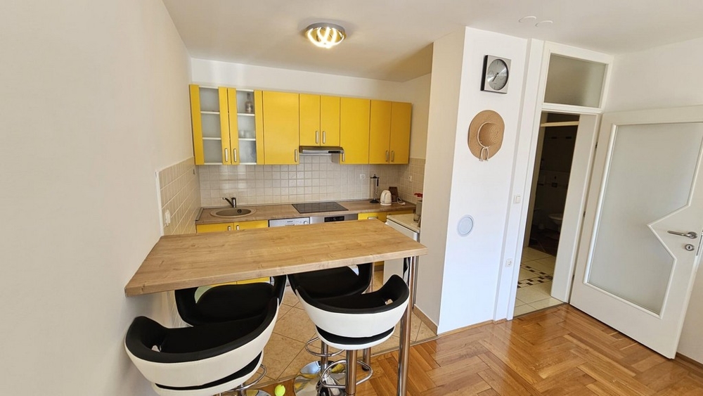 Kuchyňa so žltými vstavanými skriňami a barovým pultom