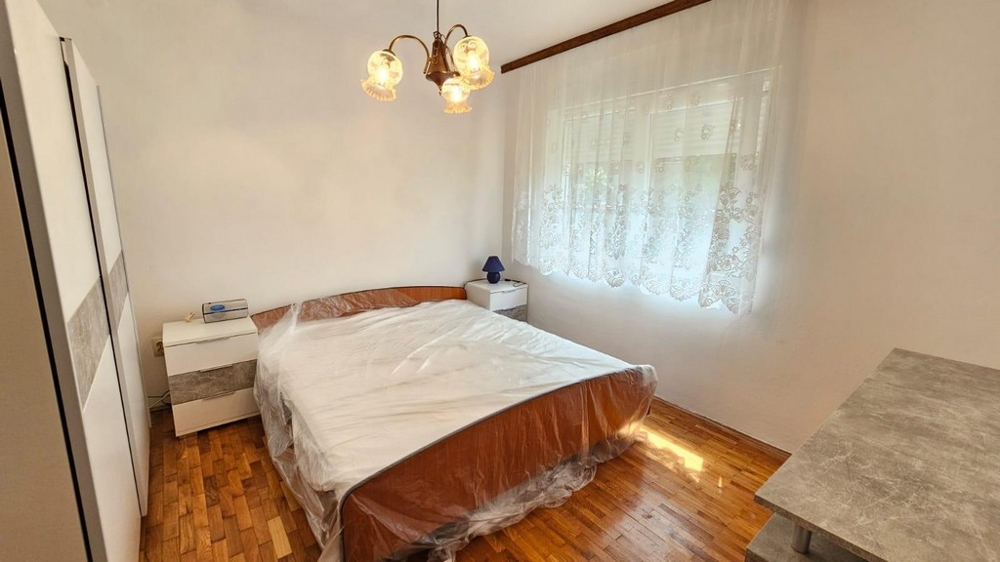 Spálňa s manželskou posteľou, skriňou a oknom s denným svetlom