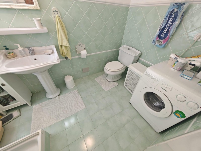 Kúpeľňa s práčkou a zelenými obkladmi