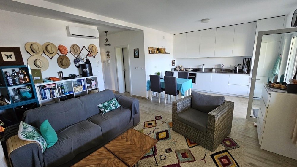 Obývacia izba s pohovkou, kreslom a otvorenou kuchyňou