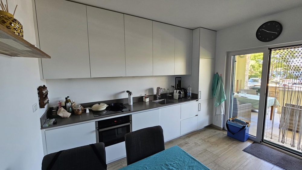 Moderná biela kuchyňa s jedálenským kútom a vstupom na terasu