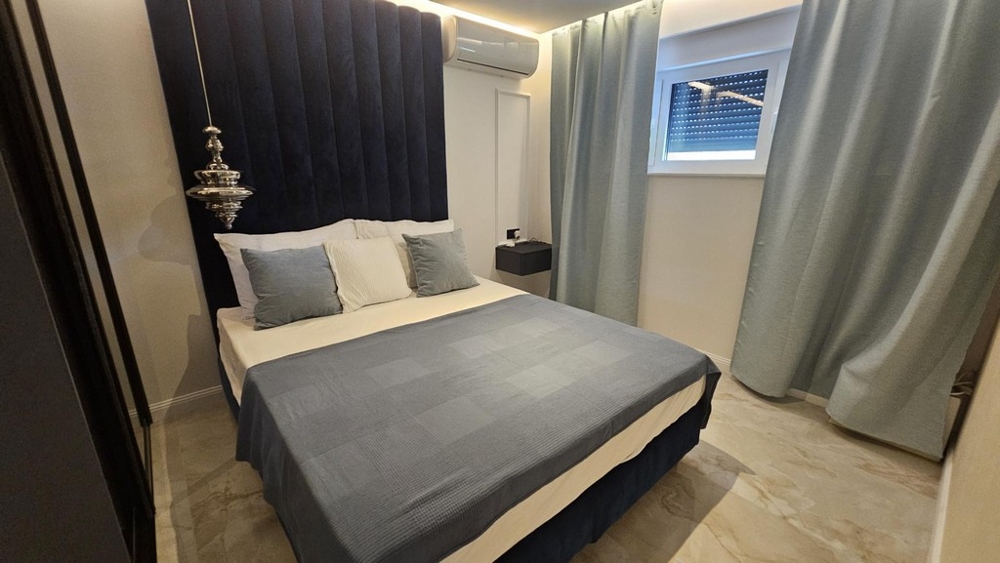 Spálňa s manželskou posteľou a tmavomodrým čelom