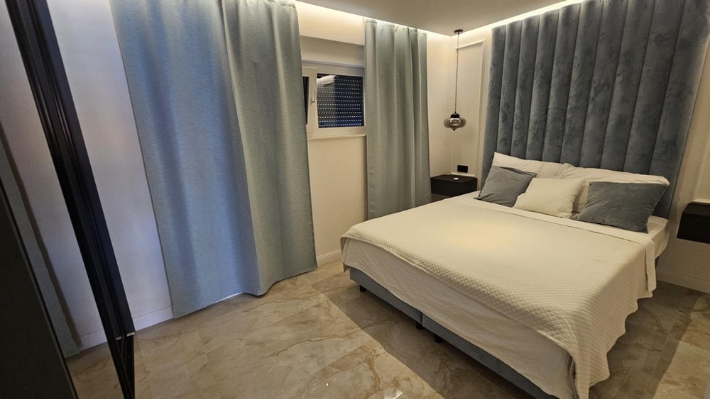 Spálňa s manželskou posteľou a svetlomodrým čelom