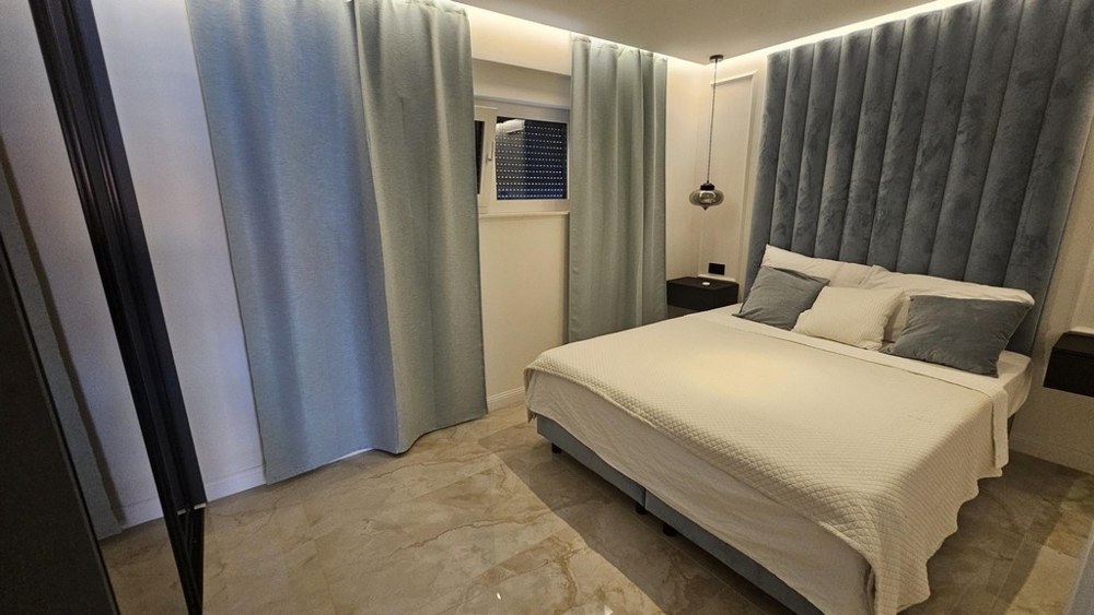 Spálňa s manželskou posteľou a svetlomodrými závesmi