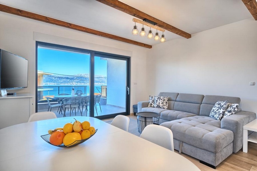 Obývacia izba s pohovkou a prístupom na terasu s výhľadom na more