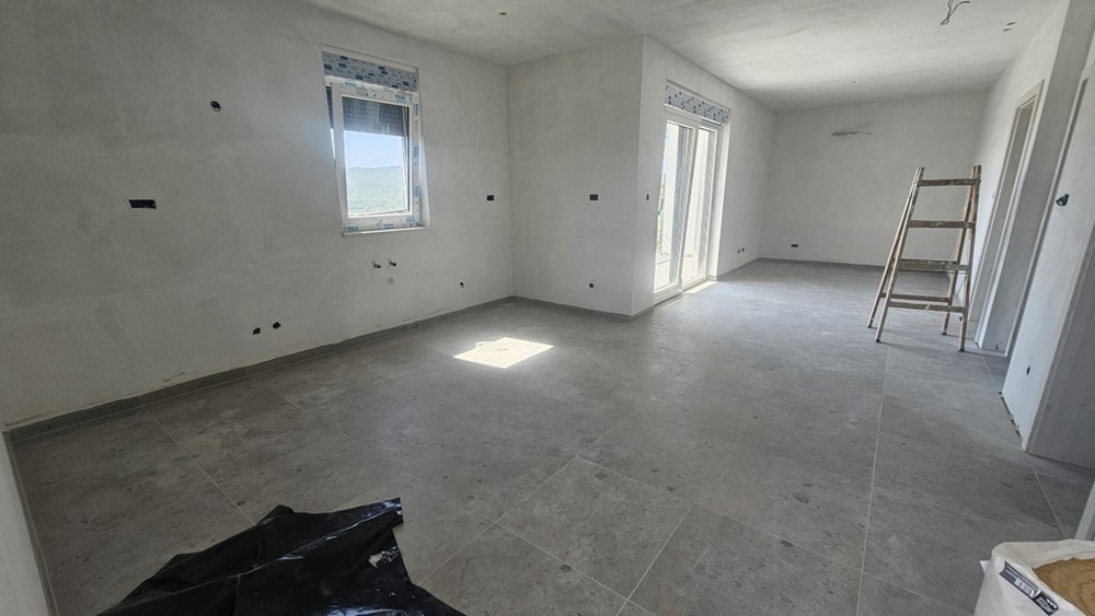 Svetlý obývací a kuchynský priestor s veľkými oknami v novostavbe na Krku