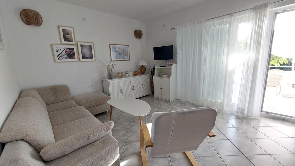 Svetlá obývacia izba s pohovkou, kreslom a prístupom na terasu