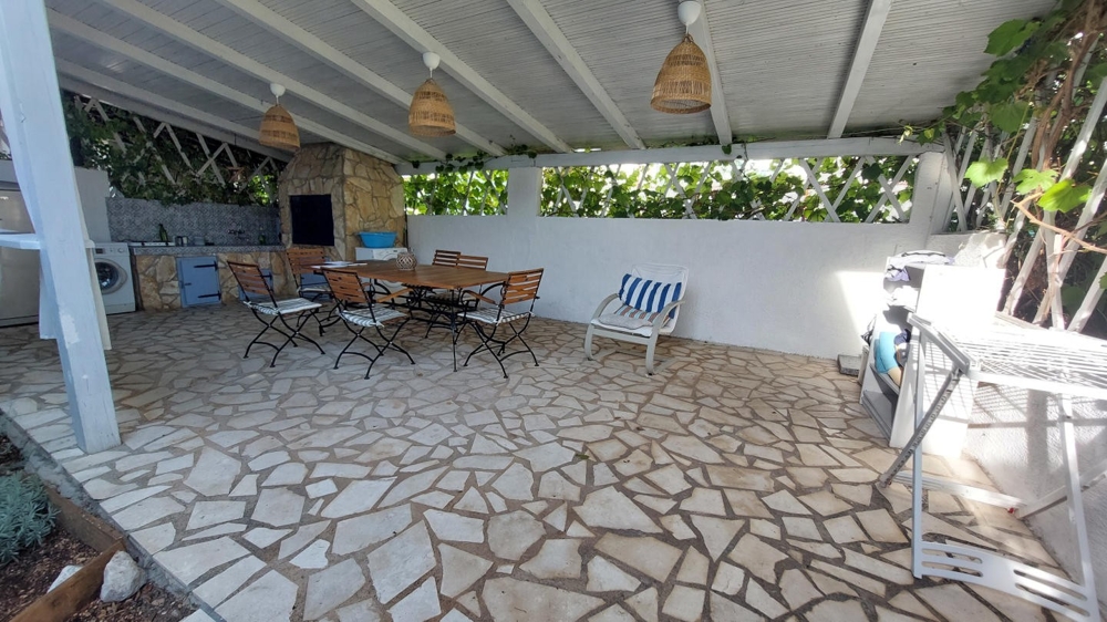 Krytá letná kuchyňa s jedálenským stolom a grilom