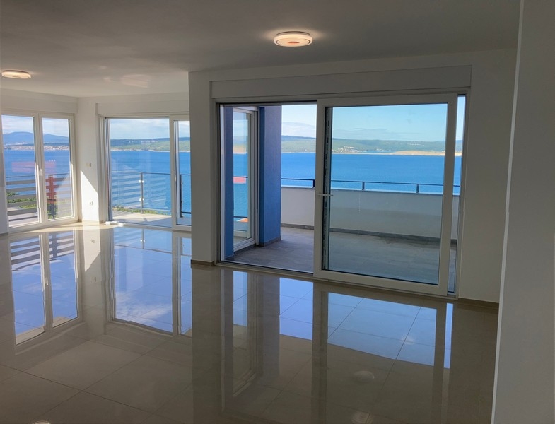 Obývacia izba s veľkými oknami a výhľadom na more