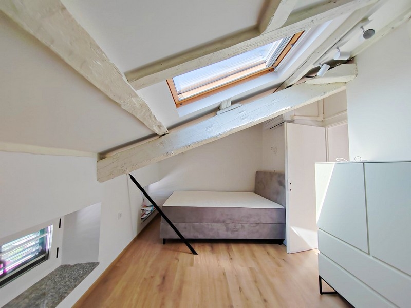 Druhá spálňa v podkroví s posteľou a strešnými trámami