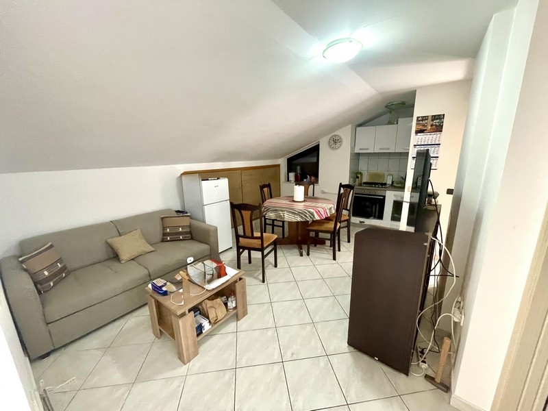 Obývacia izba s pohovkou, jedálenským stolom a integrovanou kuchyňou