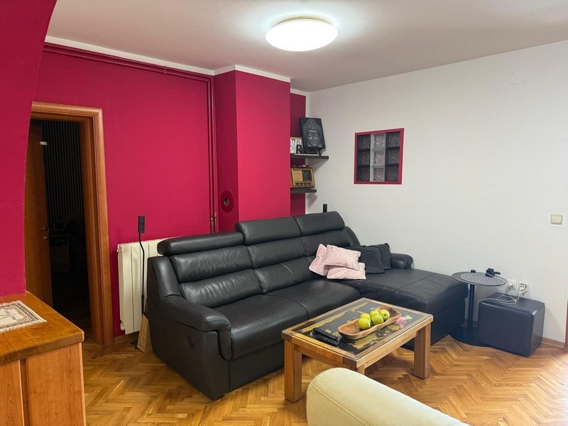 Obývacia izba s čiernou koženou pohovkou a konferenčným stolíkom