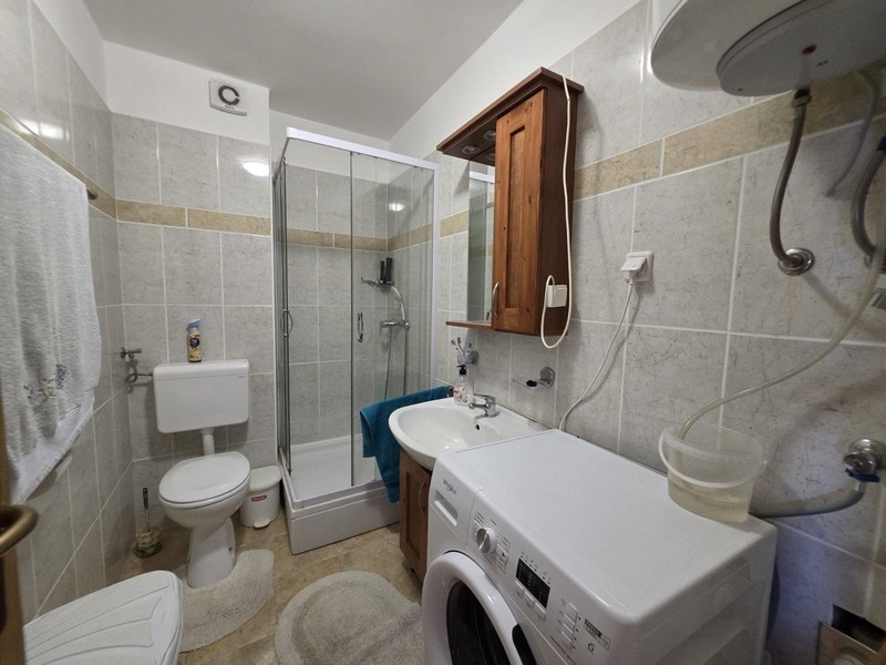 Kúpeľňa so sprchovým kútom, práčkou a dlažbou