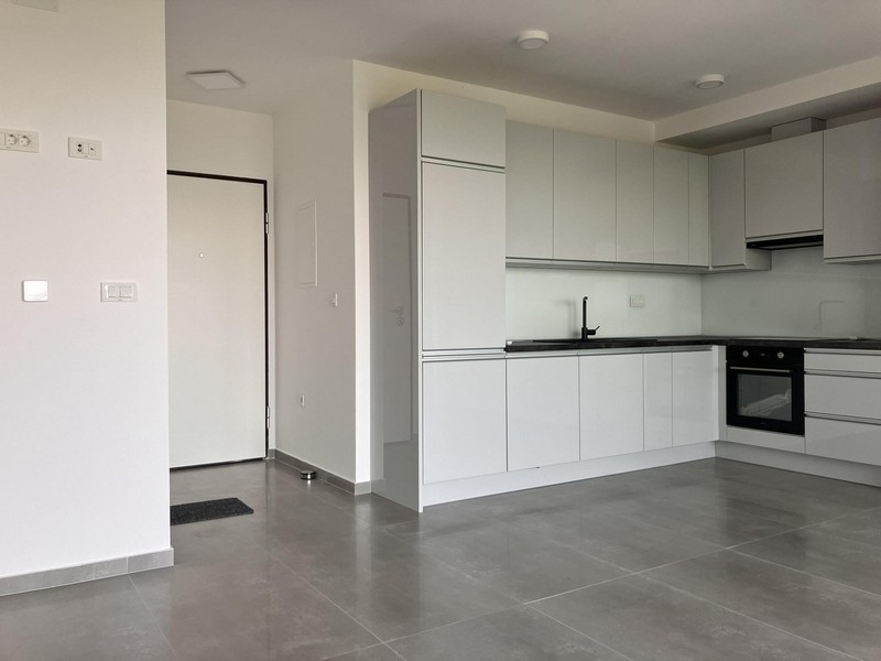 Otvorená kuchyňa s bielou vybavenou kuchyňou a dláždenou podlahou