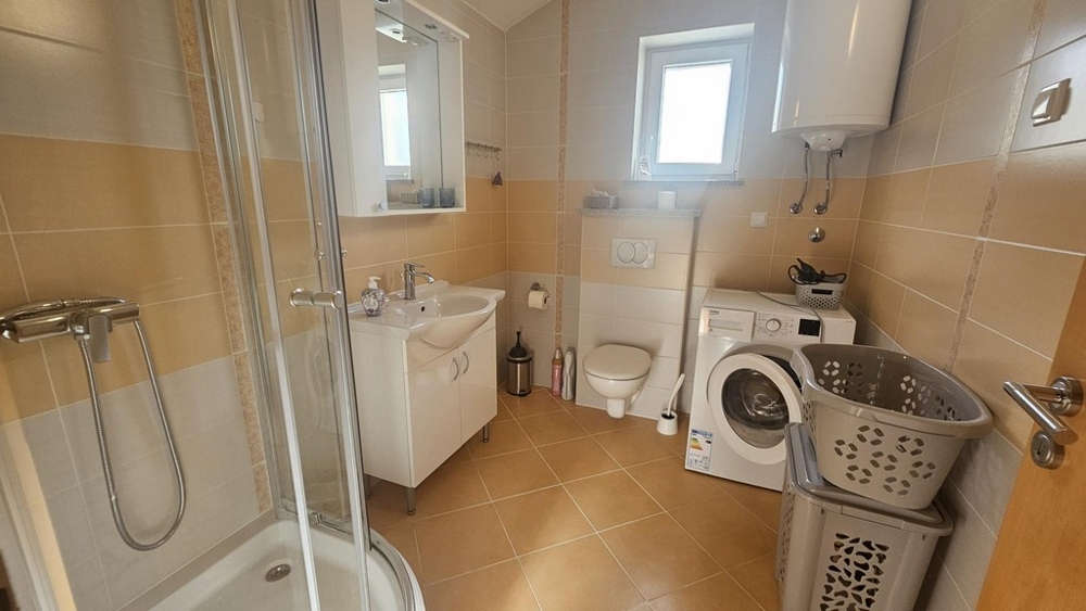 Kúpeľňa so sprchovacím kútom, práčkou a oknom