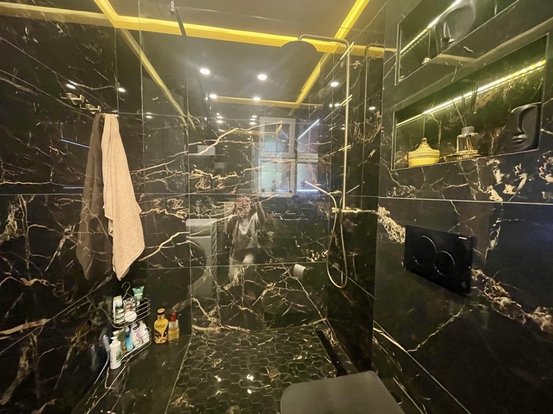 Kúpeľňa s veľkým sprchovacím kútom a čiernym mramorovým dizajnom