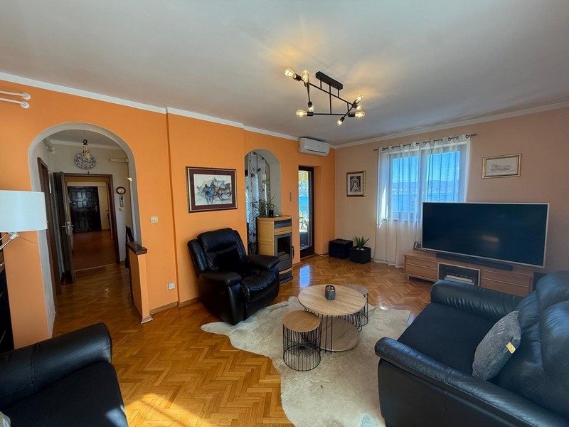 Obývacia izba s čiernou koženou pohovkou a TV