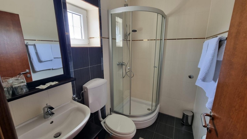 Kúpeľňa s tmavými obkladmi a sprchovacím kútom.