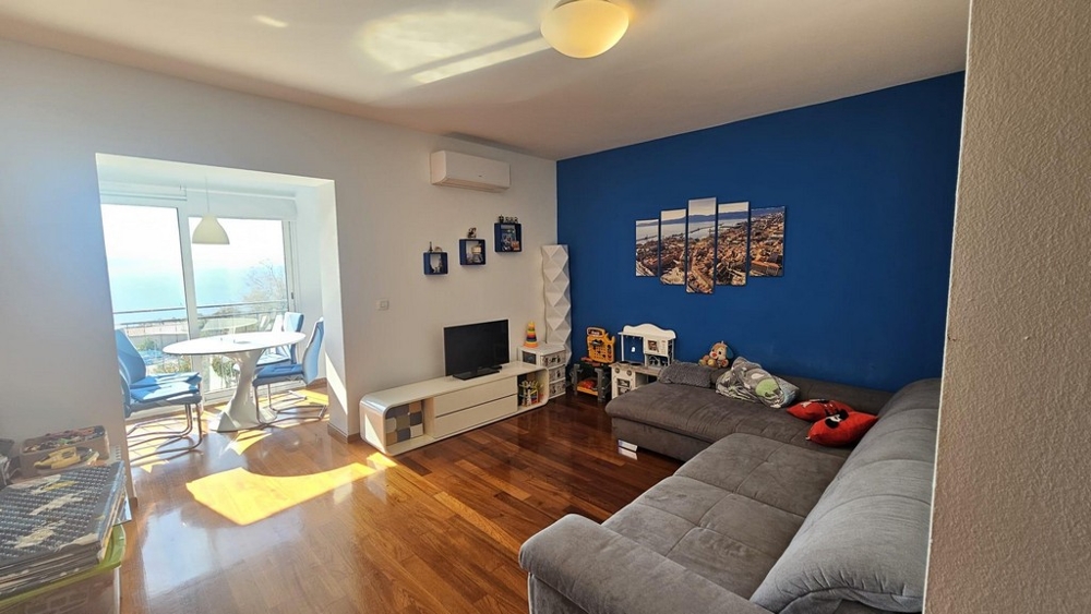 Obývacia časť so sivou rohovou pohovkou a dizajnom modrej steny