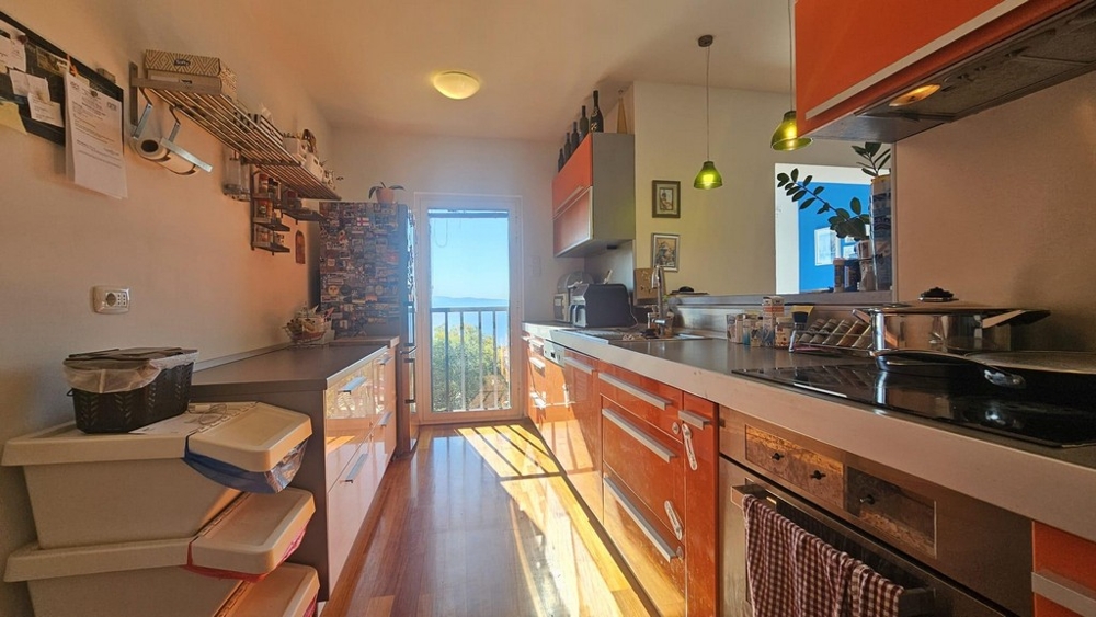 Kuchyňa s oranžovými frontami a výhľadom na more cez balkónové dvere