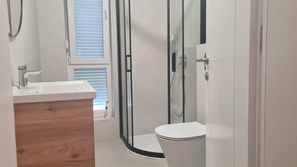 Moderná kúpeľňa so sprchovacím kútom a dreveným umývadlom