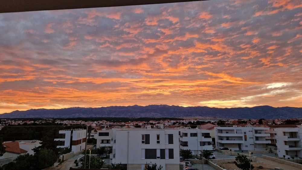 Večerná atmosféra nad Novaljou s výhľadom na pohorie Velebit
