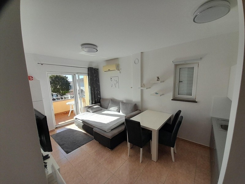 Obývacia izba s pohovkou, jedálenským stolom a prístupom na balkón s výhľadom na more