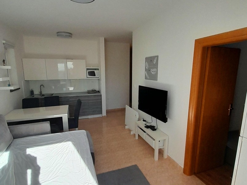 Obývacia izba s TV, jedálenským stolom a vstupom do spálne