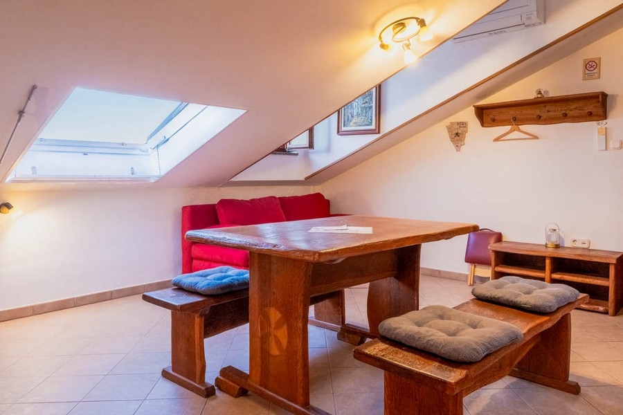 Obývacia izba so šikmým stropom a dreveným nábytkom