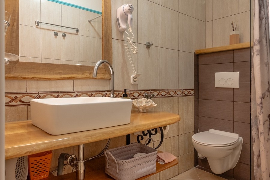 Kúpeľňa so sprchovacím kútom a dreveným umývadlom