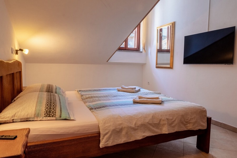 Spálňa s manželskou posteľou a nástennou TV