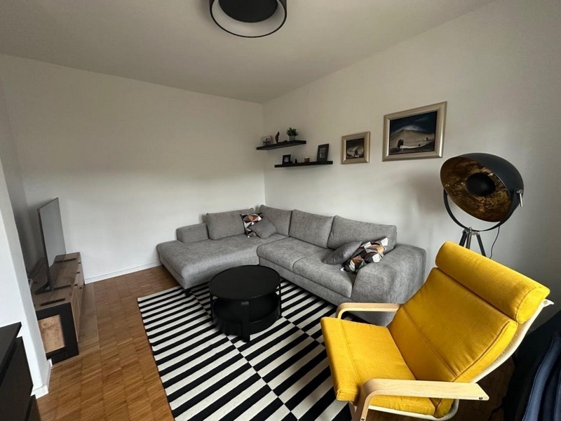 Obývacia izba so sivou rohovou pohovkou a žltým kreslom