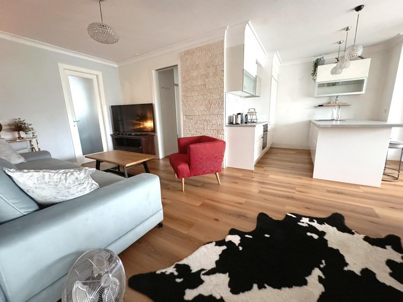 Obývacia izba s pohovkou, červeným kreslom a otvorenou kuchyňou