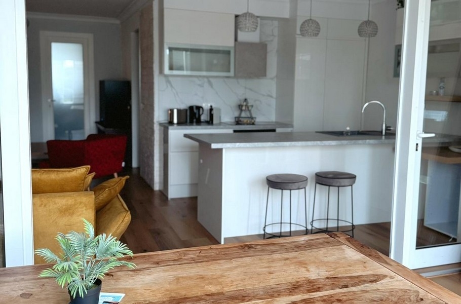 Drevený stôl a pohľad do bielej kuchyne