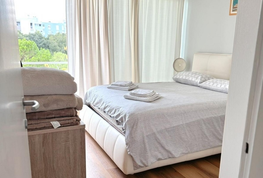 Spálňa s manželskou posteľou a svetelnými závesmi