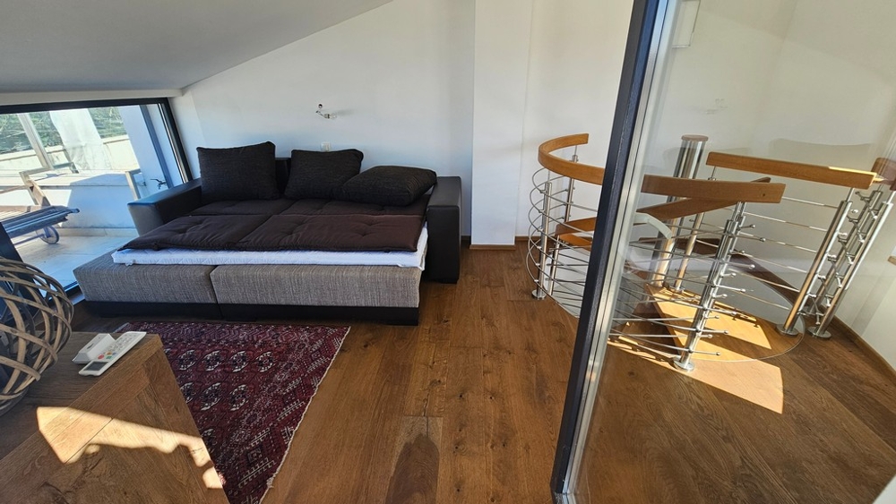 Galéria s pohovkou a točitým schodiskom do nižšej úrovne